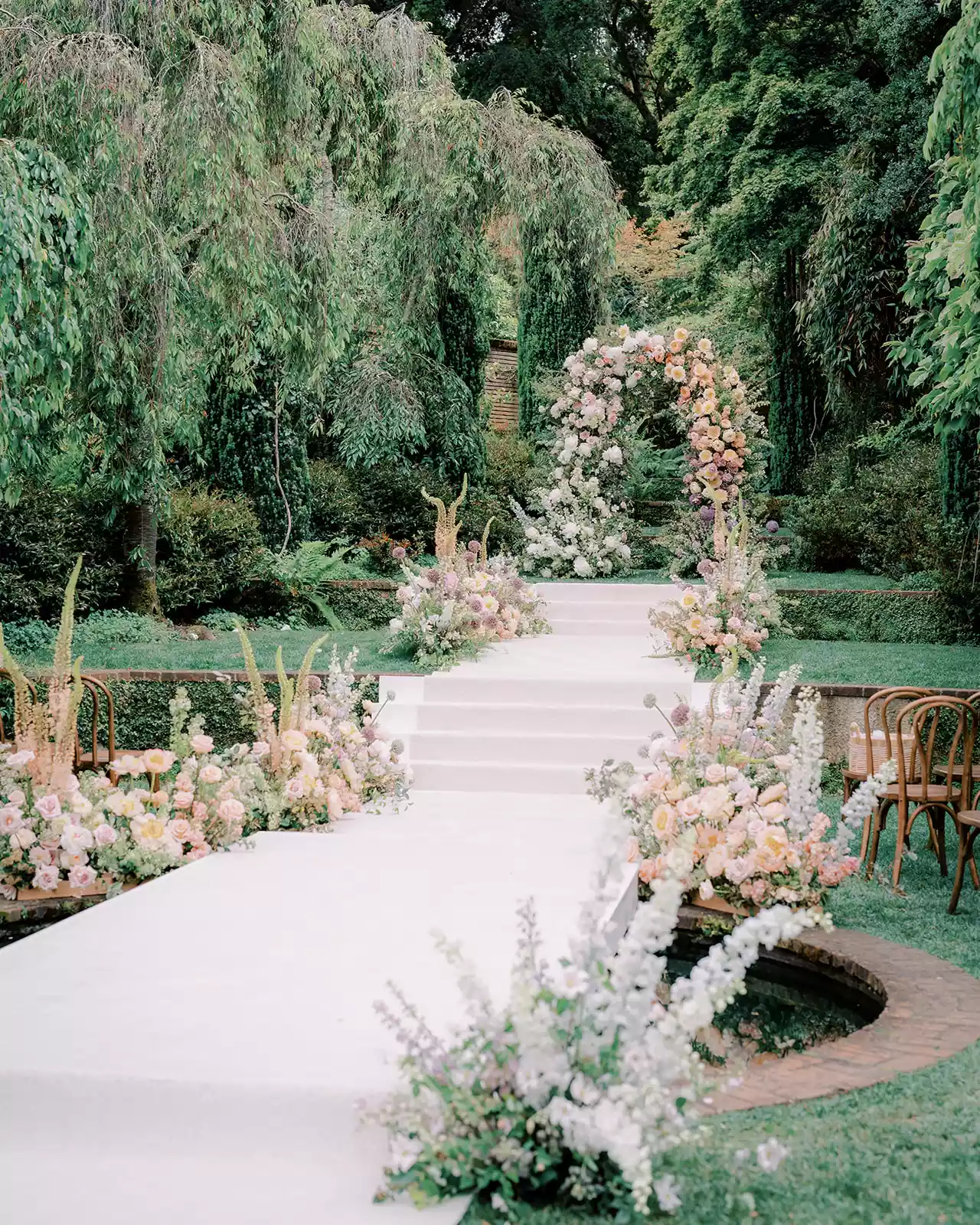 Outdoor Wedding Ceremony White Aisle With Light Pink, Orange, and Purple Flower Decor