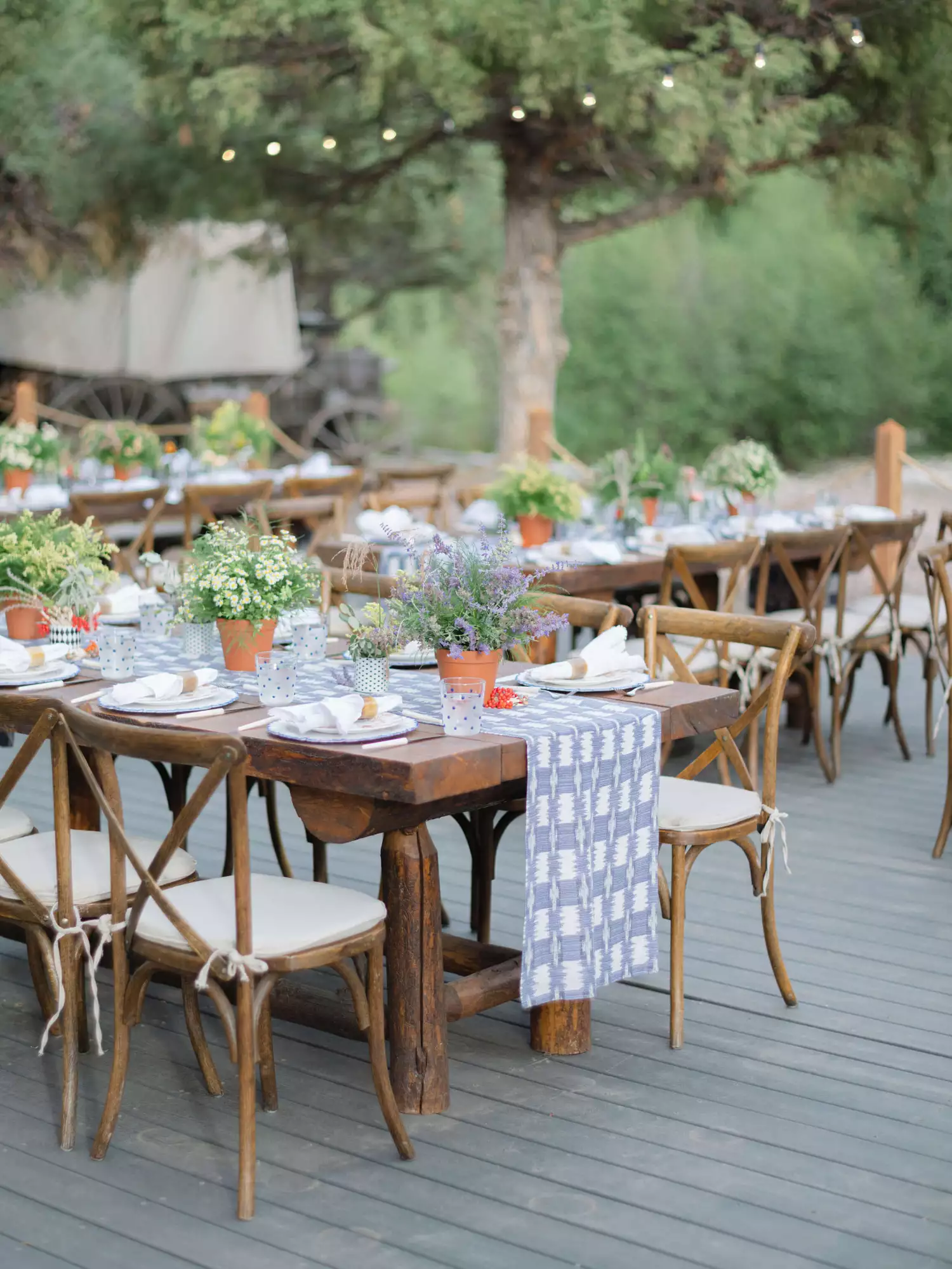 Wooden tables and chairs with denim-inspired runners and potted plants for the rehearsal dinner