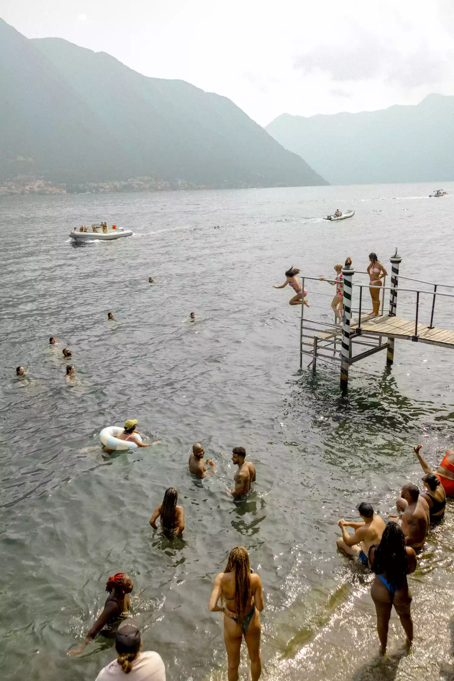 Guests jumping off of a dock and swimming in Lake Como