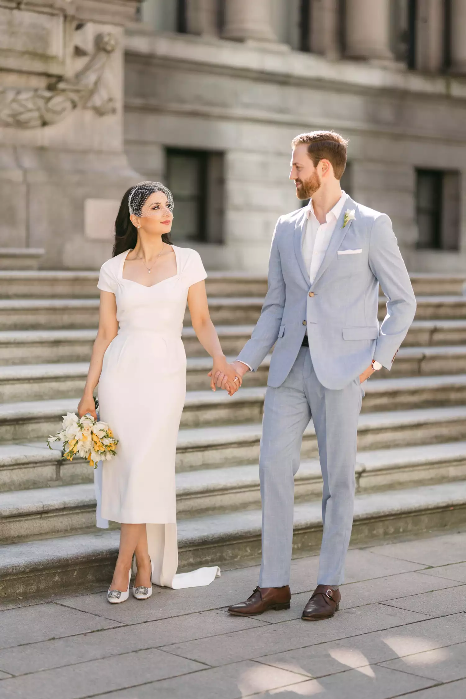 bride and groom holding hands outside of a courthouse