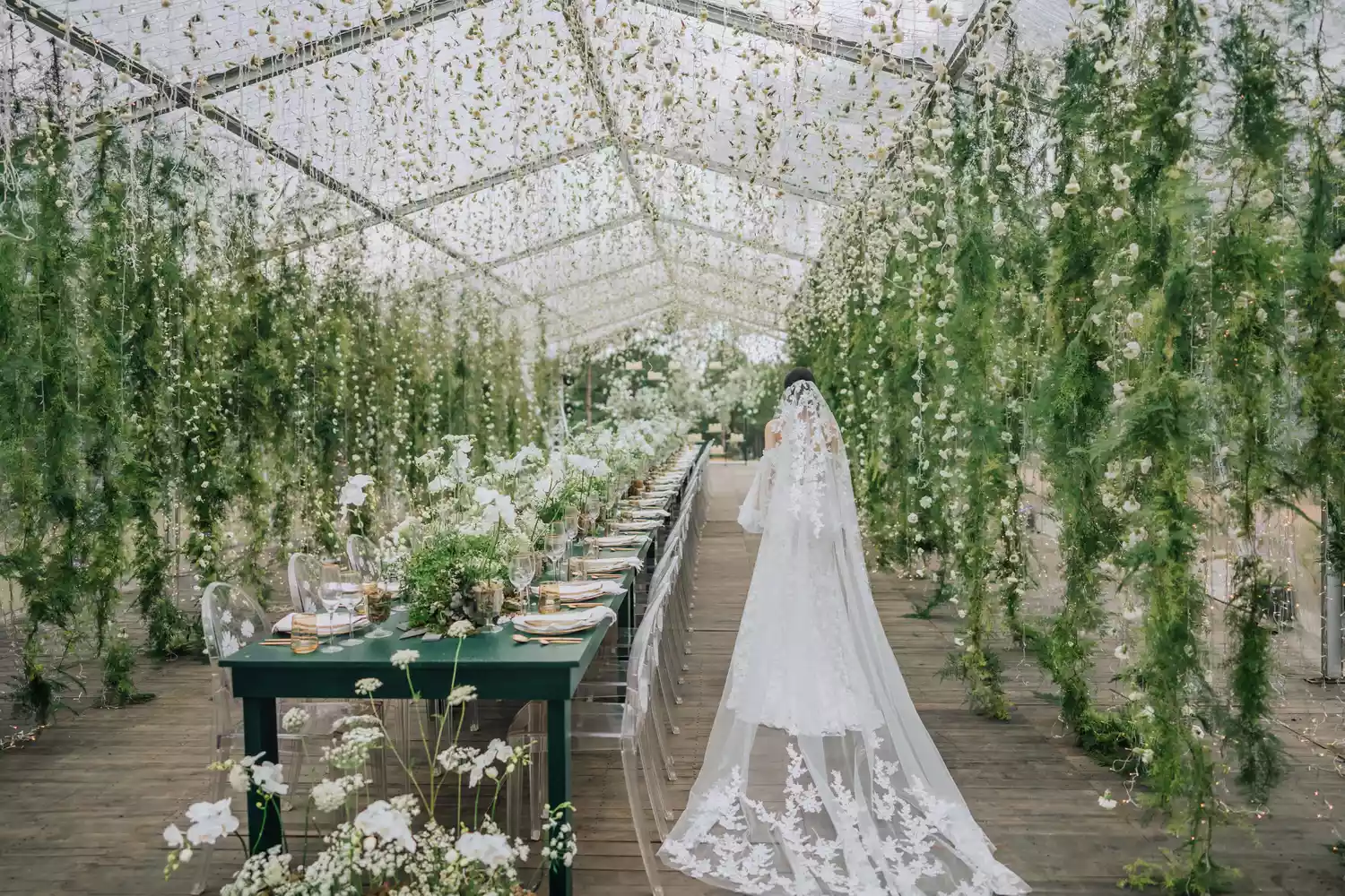 photo of the back of a bride walking through her wedding reception held in a greenhouse