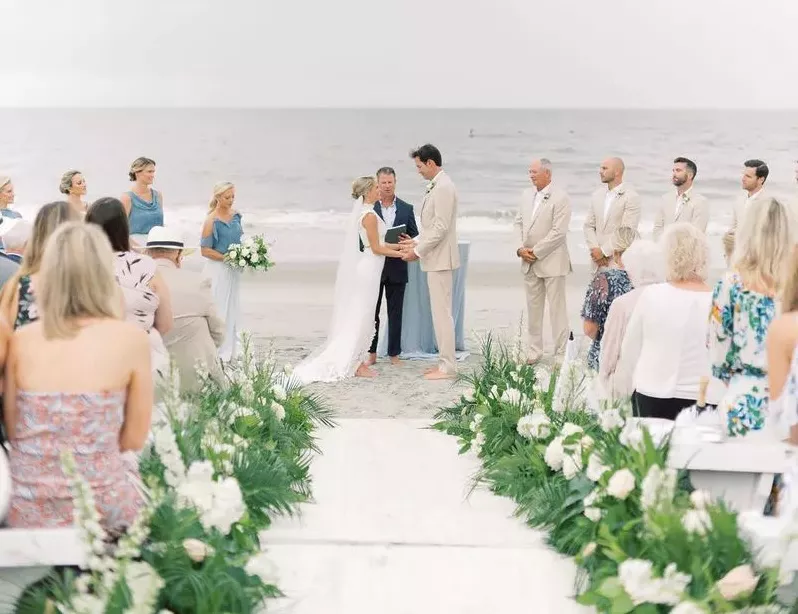 Bride and groom exchanging vows on the beach during a beachside wedding.