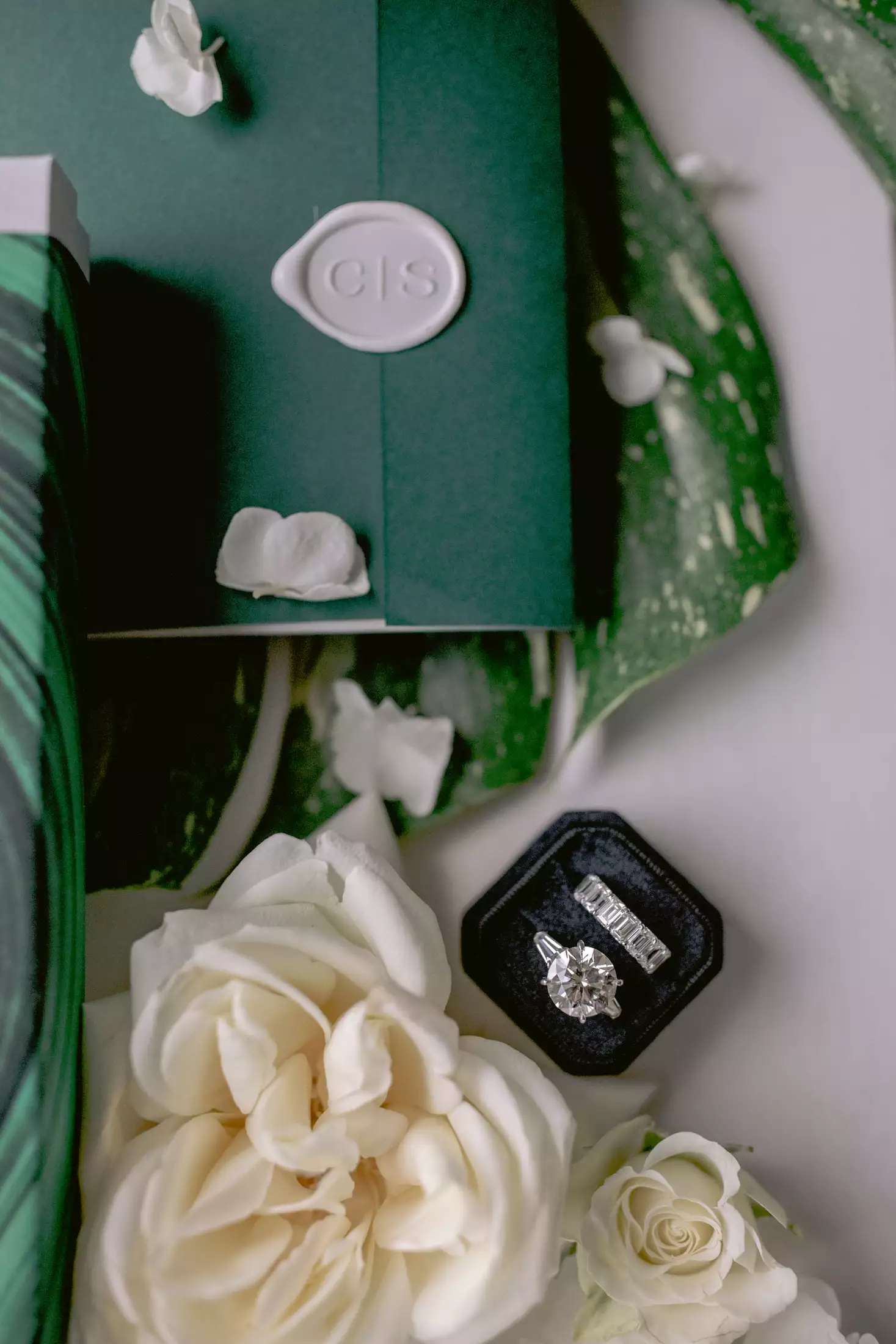 styled shot of an engagement ring and wedding band with a white rose