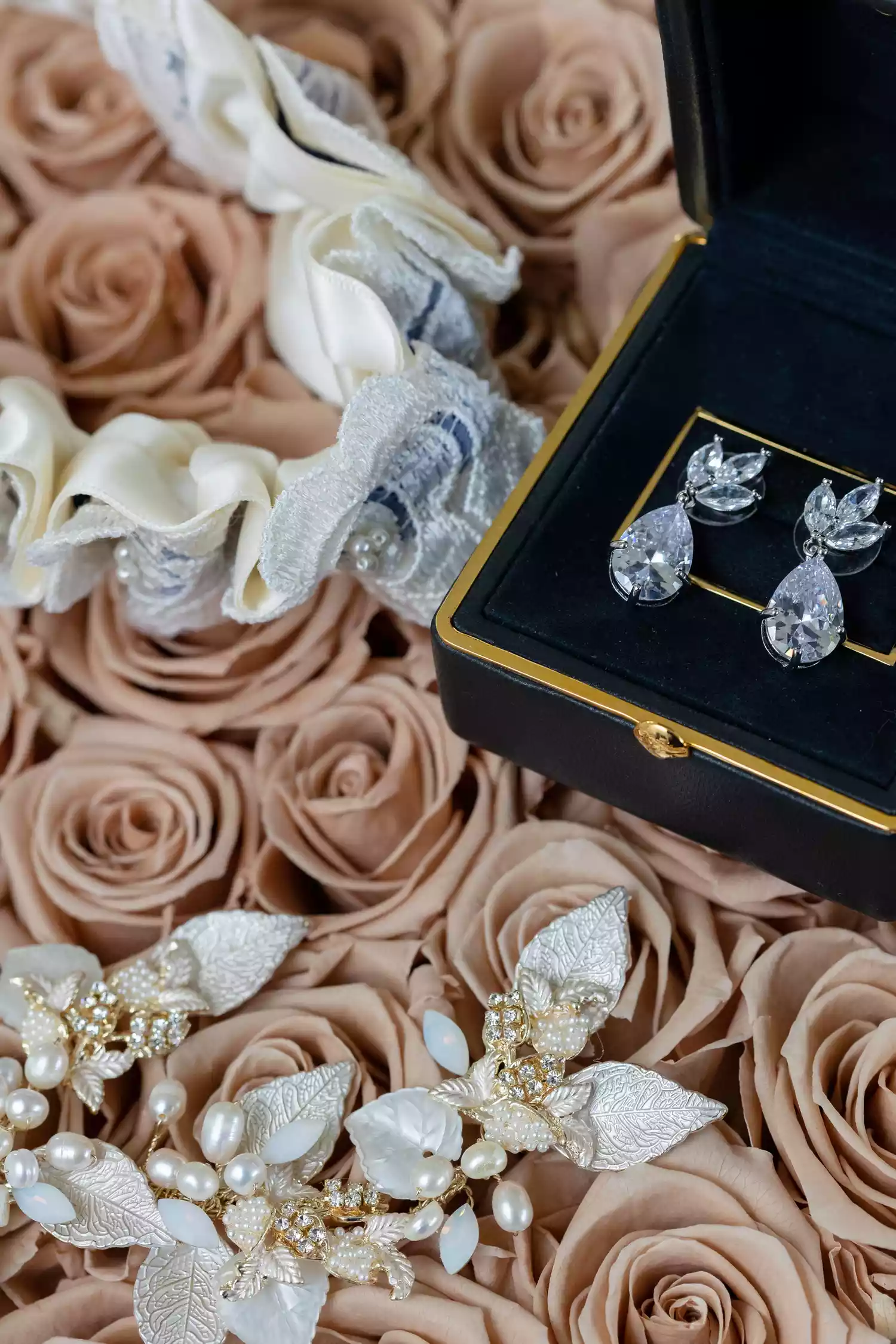 still shot of diamond wedding earrings sitting on top of peach roses