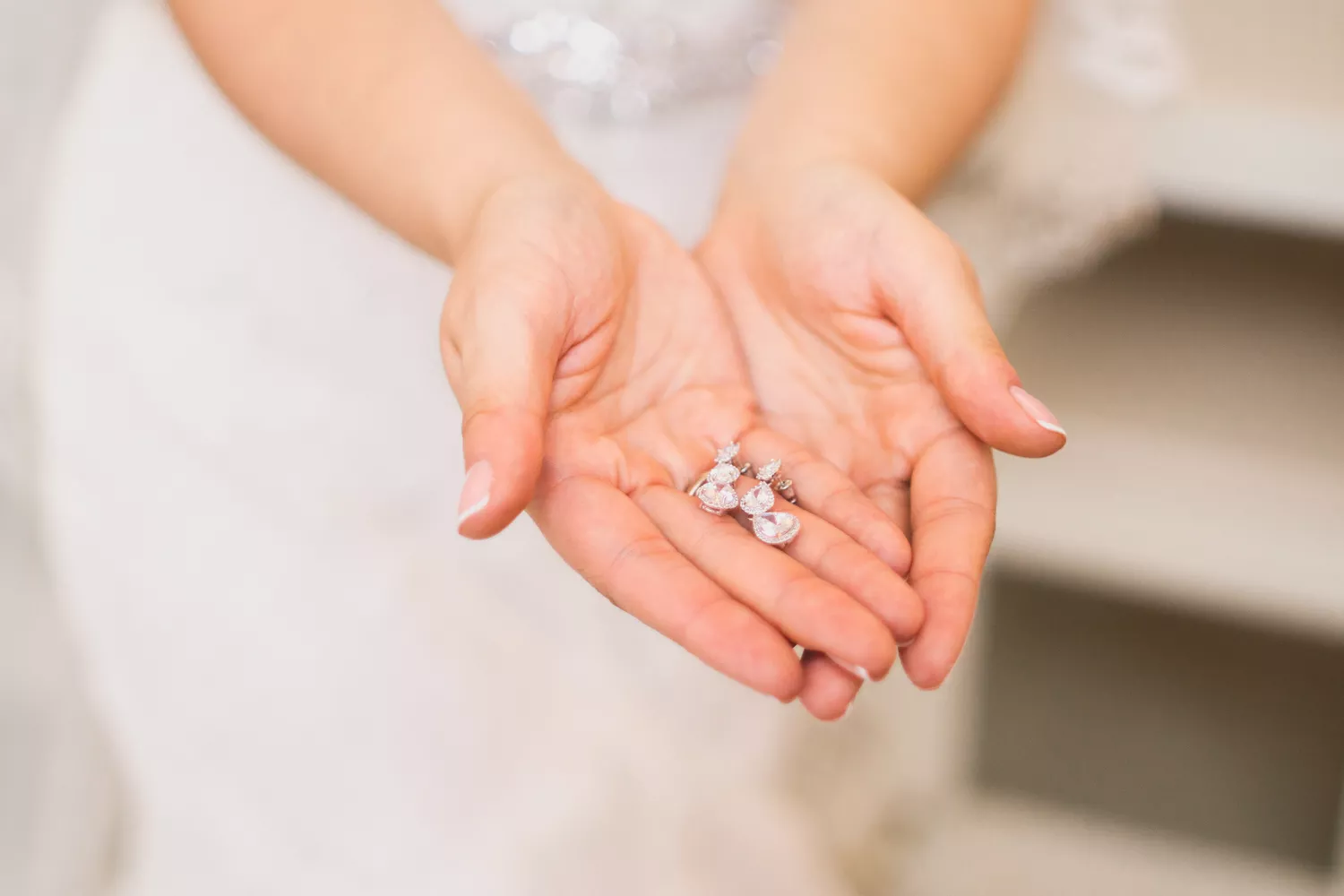 bride holding diamond drop earrings in her hand