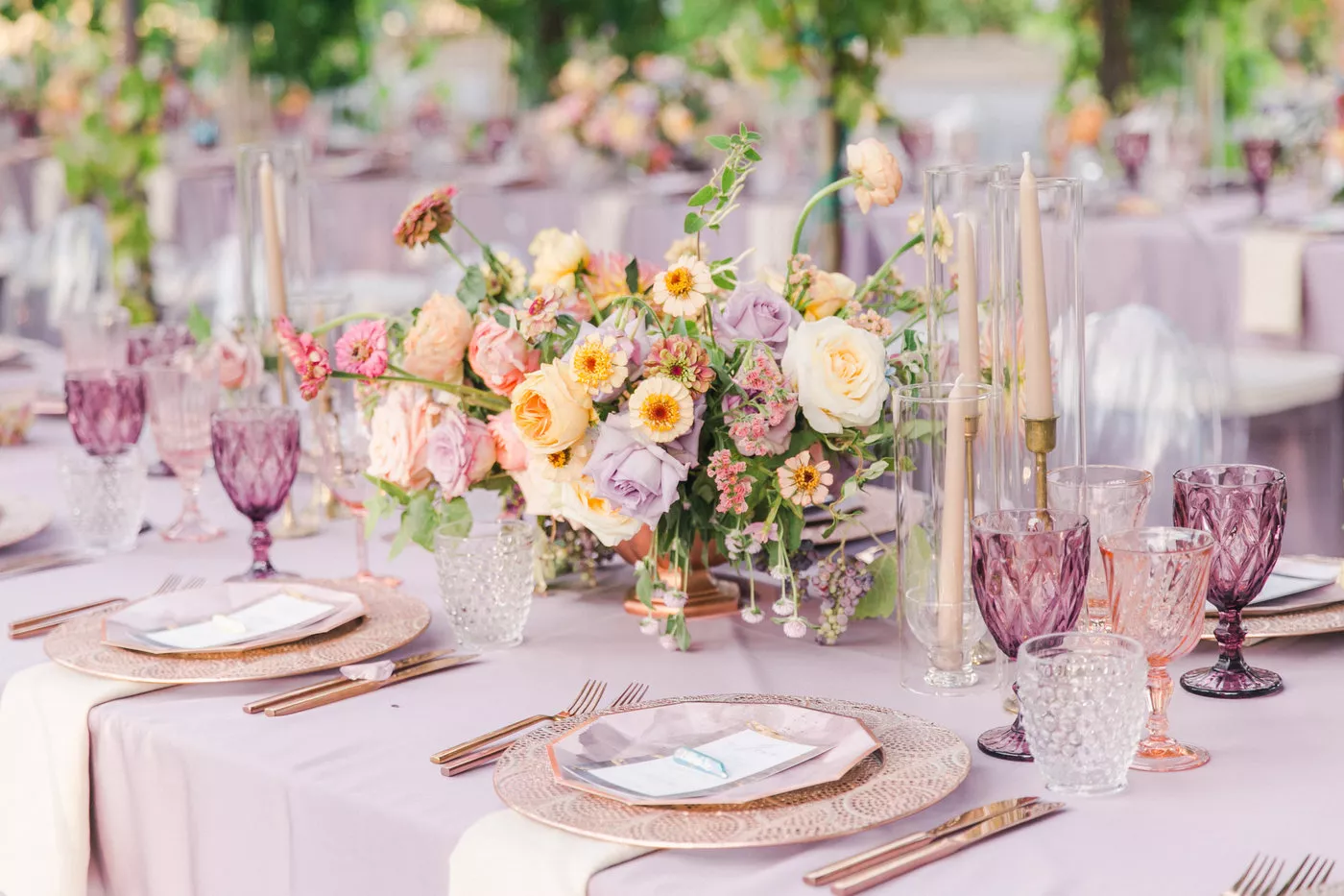 Tablescape with pink linen, pink glassware, nude candles, pink place settings, rose gold flatware, and pastel florals