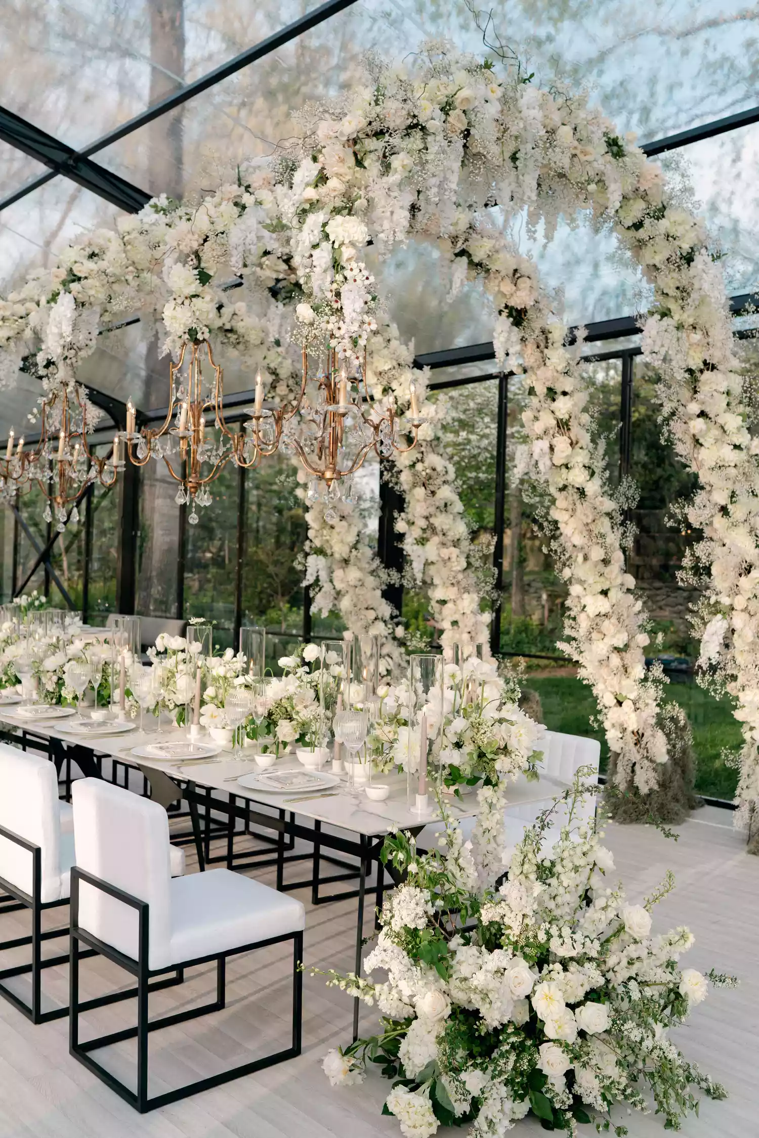 floral arches decorated with white roses holding hanging chandeliers