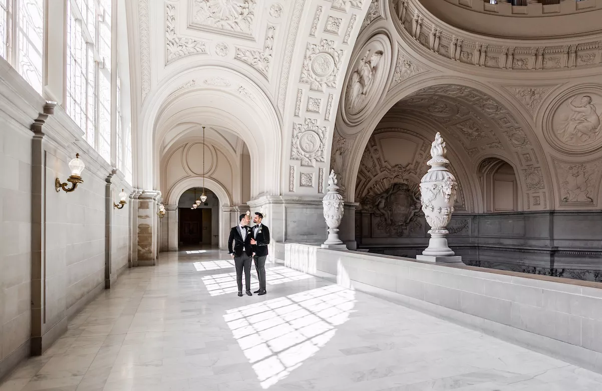 same-sex couple standing in the hallways of city hall taking their wedding portraits
