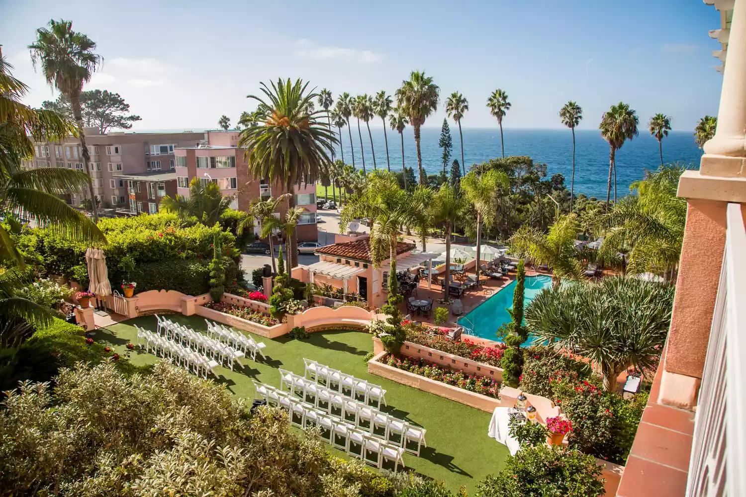 Aerial shot of wedding ceremony set-up at Hotel Valencia with ocean views, palm trees, and pool.