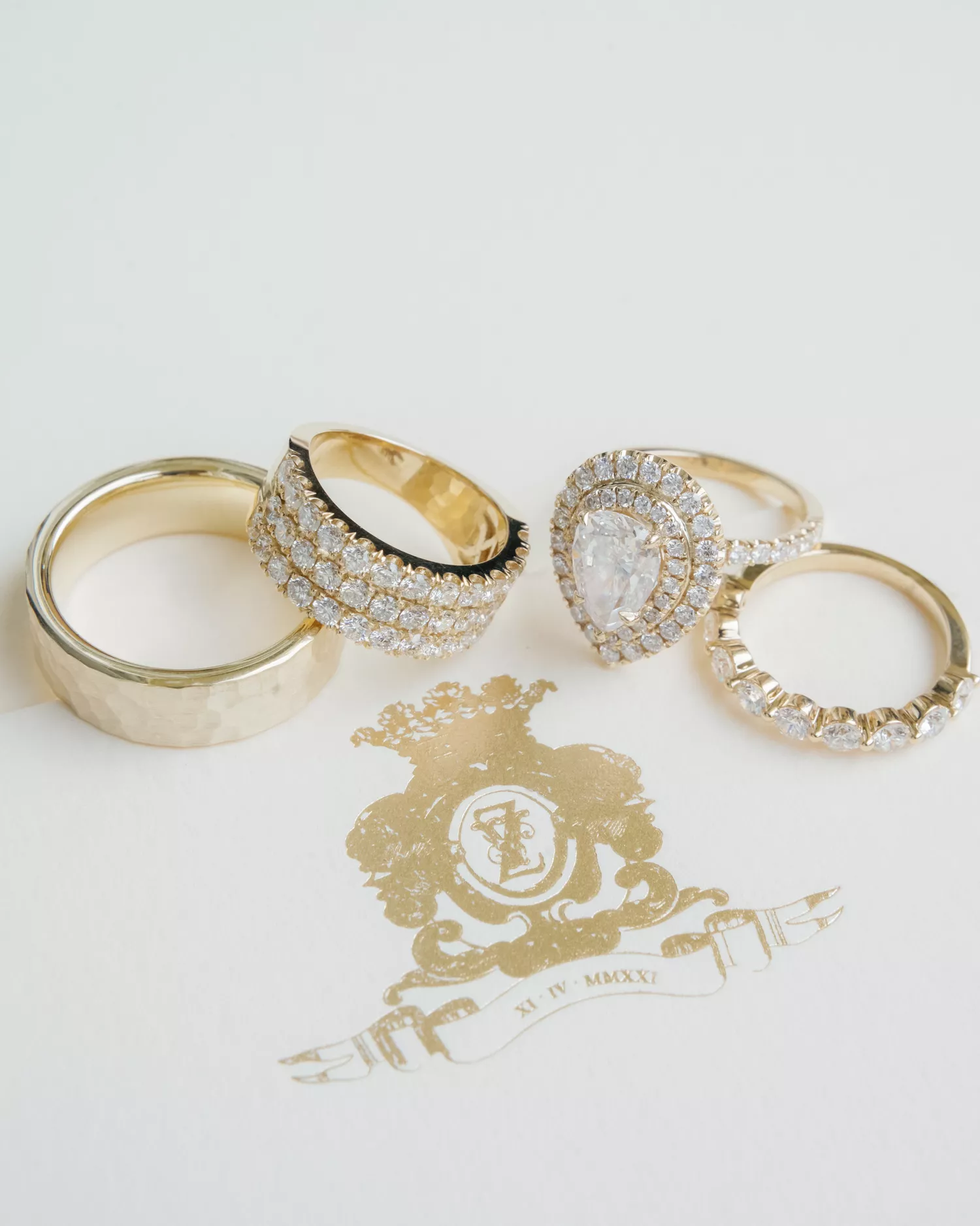 three gold diamond wedding bands and a pear-shaped engagement ring