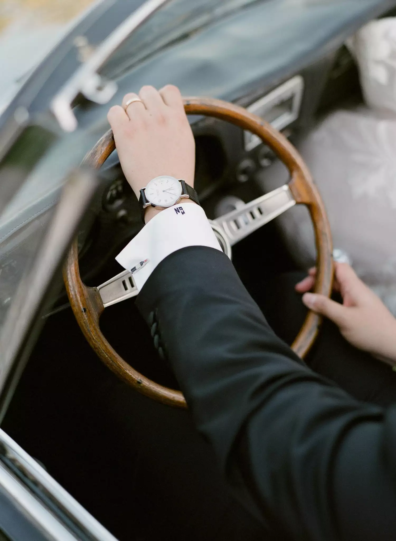 groom holding steering wheel of vintage car on wedding day