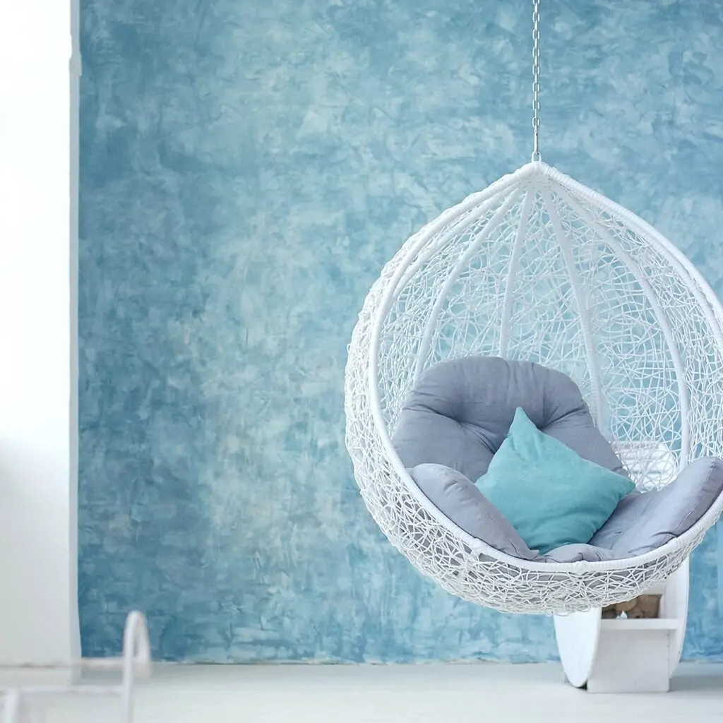 Hanging chair on a light blue wall in a small indian home