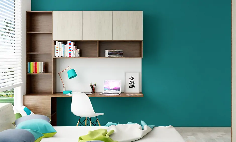 Wall attached study table with shelves in brown and cream laminate against the blue wall looks minimalistic.