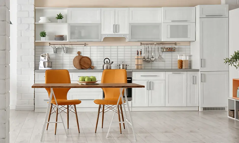 Small kitchen design with dining table in foldable style with amber-colour chairs looks minimal yet stylish.