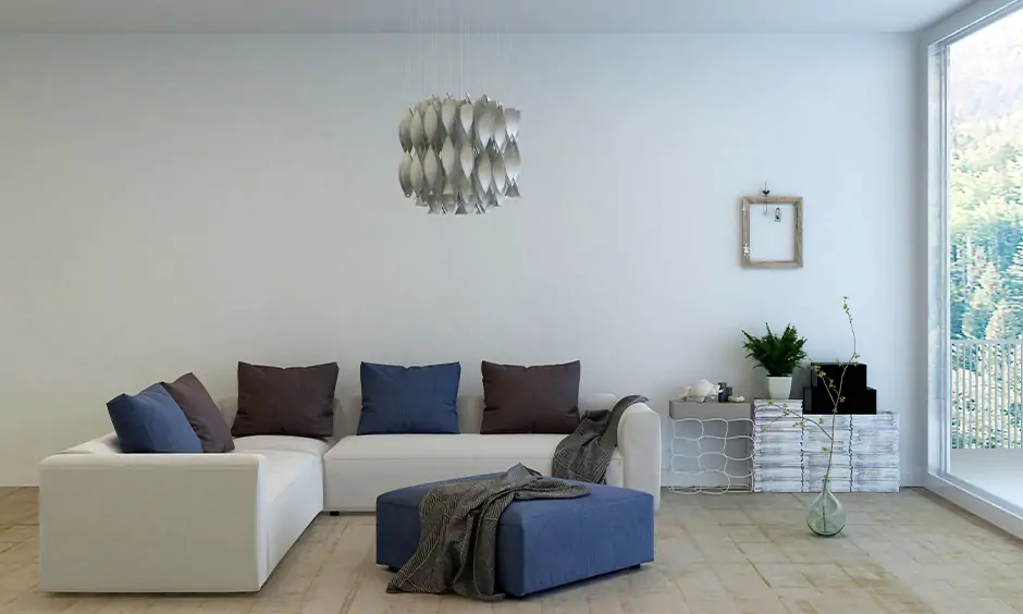 Modern living room l shape sofa in white colour with colourful pillows arranged right in the centre of the living room.