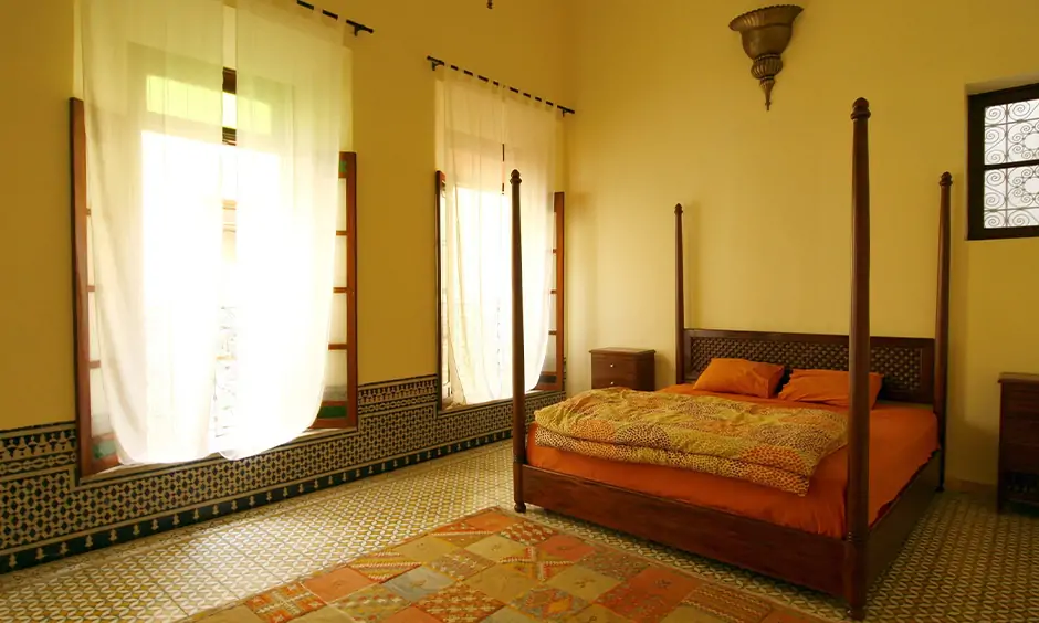 Moroccan tile pattern with the classic furniture, flowy drapes & natural light manage to infuse warmth to the bedroom.