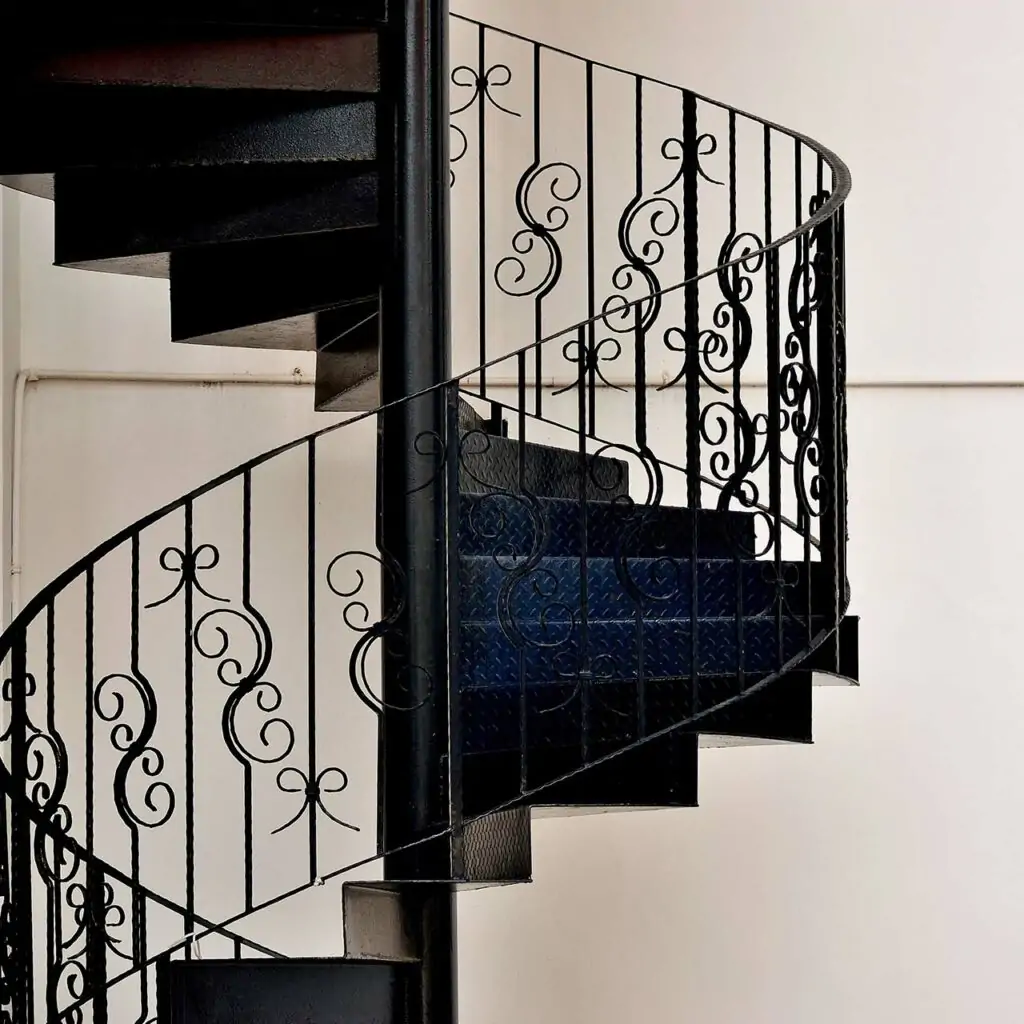 Spiral staircase design with a delicate wrought iron railing is beautiful to look for indian homes staircase design