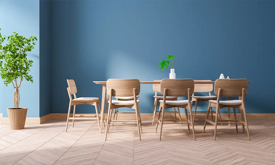 Light and stackable dining room chairs crafted from fibre against the blue wall, and they are very convenient to set up.