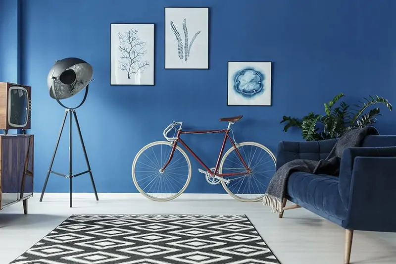 Ocean blue wall paint colors with modern art frames and a black and white patterned carpet to your living room blue house colors