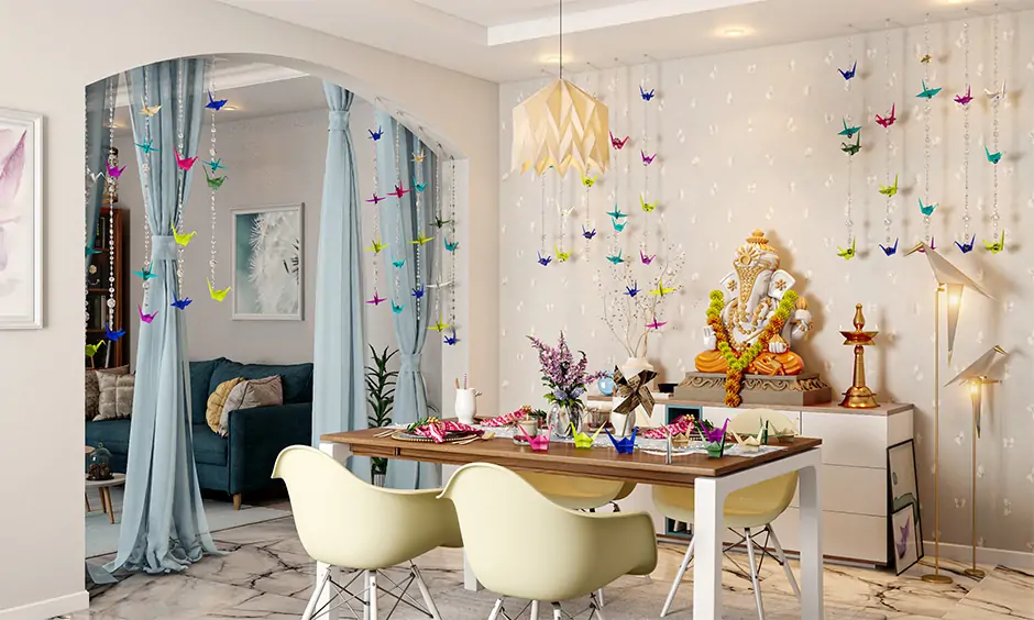 Ganpati decoration at home with origami in blues yellows and pinks colours lights in this white room look beautiful