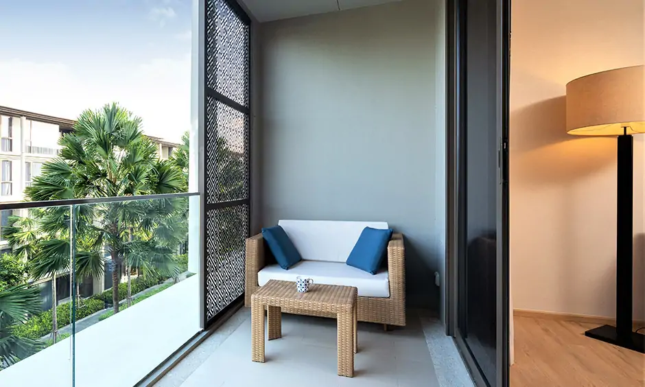 Rectangular balcony seating area with a jute two-seater sofa & table in the corner, steel and glass railings looks gorgeous.