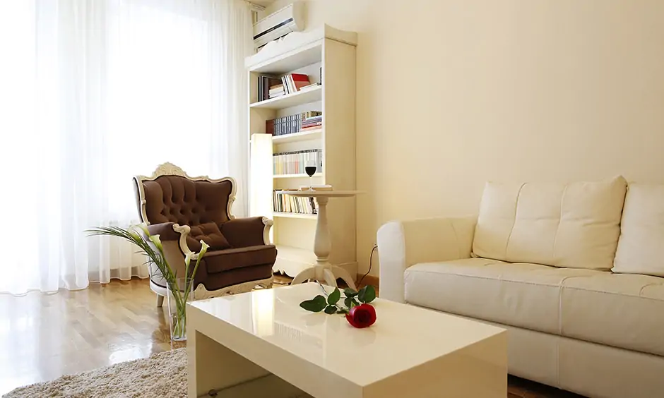 A small reading room designed in the living area features a wing chair sleek bookshelf and coffee table