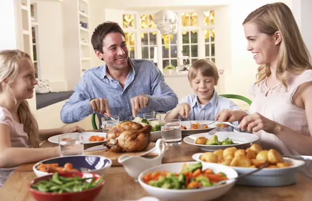 Happy family having roast chicken dinner at table