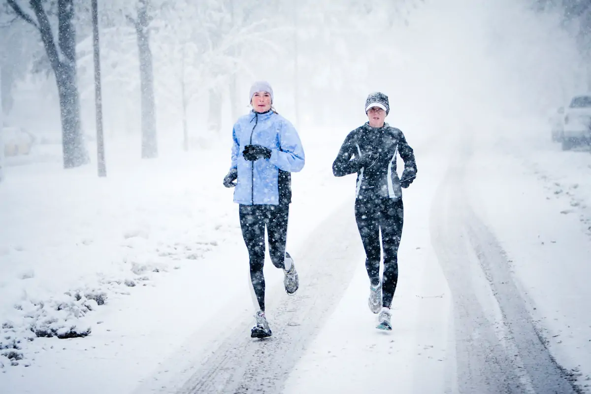 Two women run down mountain avenue in a snowstorm