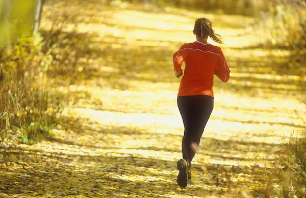 Female running on leaf laiden road during the autumn season in carbondale colorado